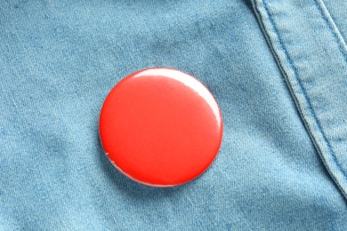 Photo of Red button badge pinned on denim shirt, top view. Mockup for design