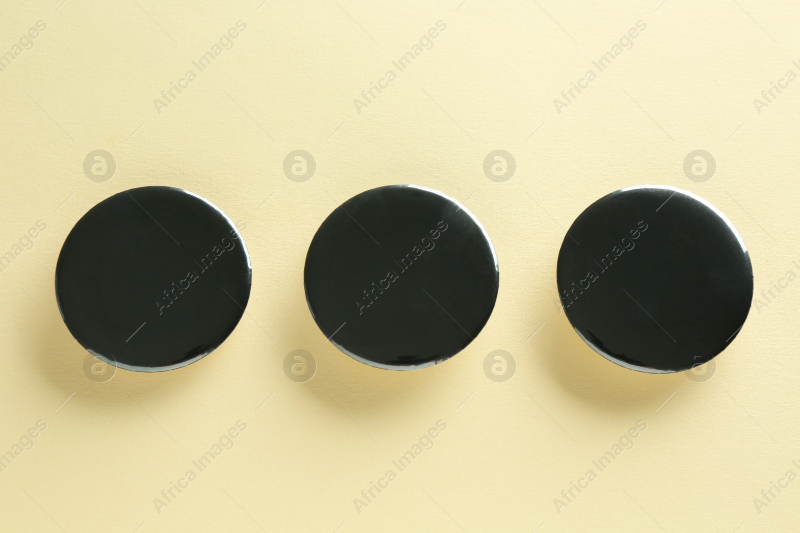 Photo of Black button badges on beige background, flat lay. Mockup for design