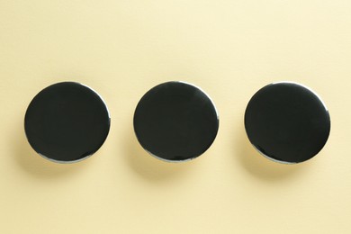 Photo of Black button badges on beige background, flat lay. Mockup for design