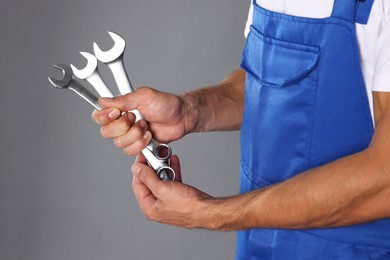 Photo of Auto mechanic with wrenches on grey background, closeup