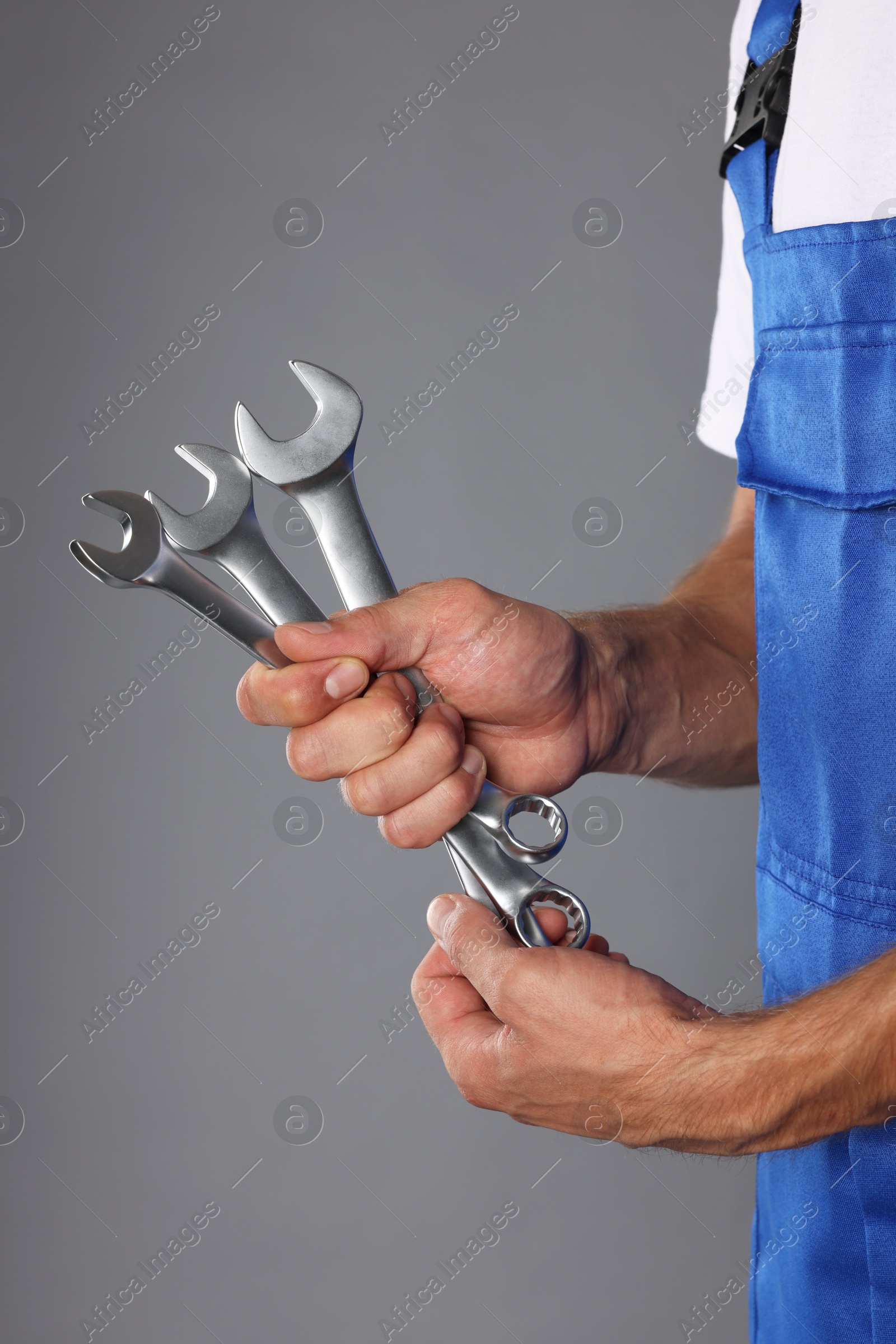 Photo of Auto mechanic with wrenches on grey background, closeup