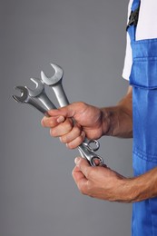 Auto mechanic with wrenches on grey background, closeup