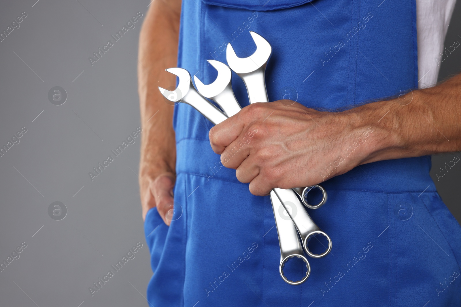 Photo of Auto mechanic with wrenches on grey background, closeup. Space for text