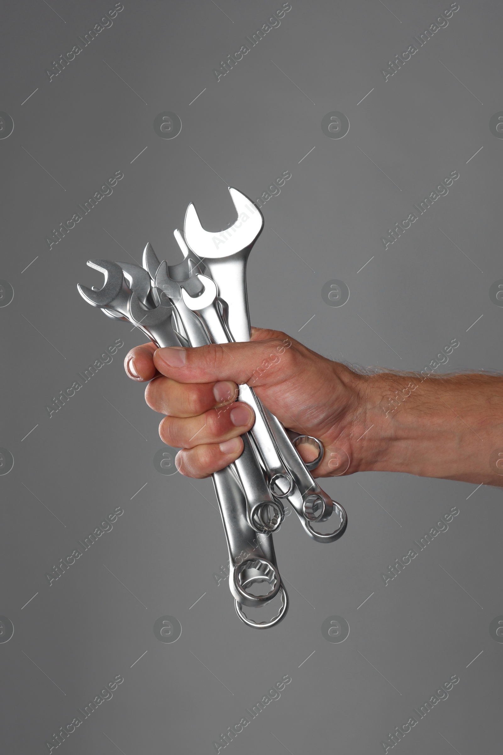 Photo of Auto mechanic with wrenches on grey background, closeup