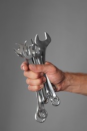 Photo of Auto mechanic with wrenches on grey background, closeup