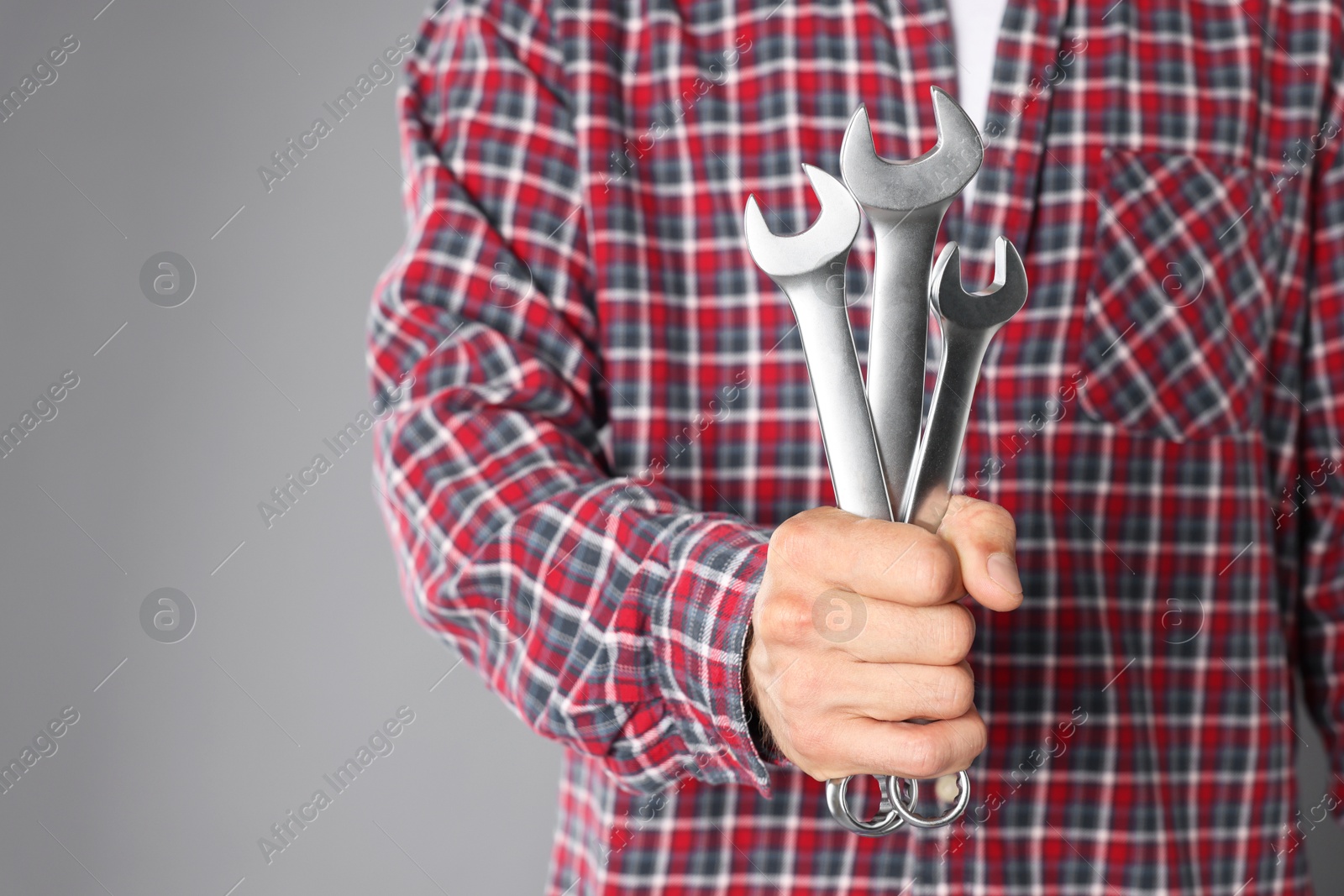 Photo of Auto mechanic with wrenches on grey background, closeup