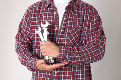 Photo of Auto mechanic with wrenches on light grey background, closeup