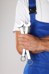 Photo of Auto mechanic with wrenches on light grey background, closeup