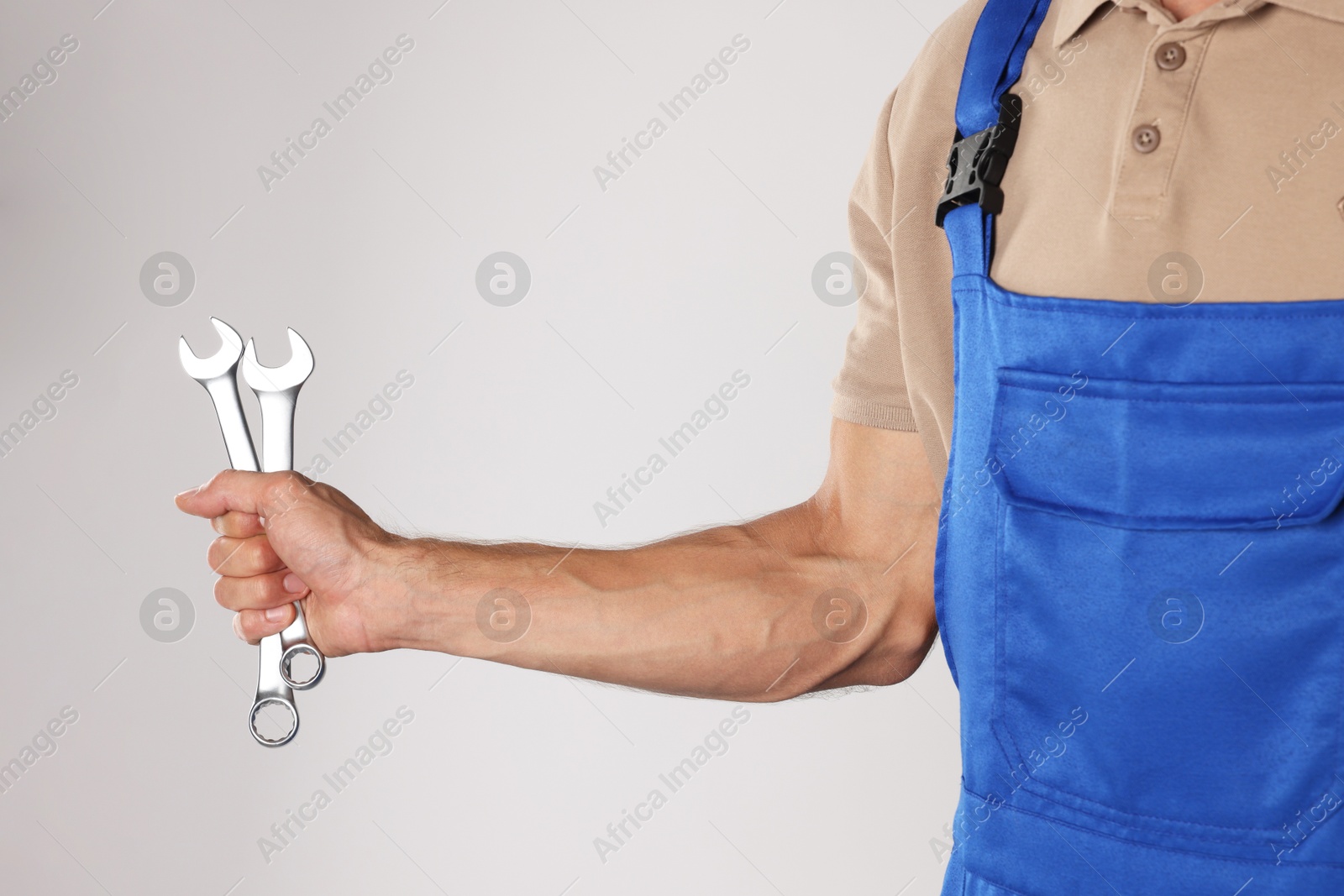 Photo of Auto mechanic with wrenches on light grey background, closeup