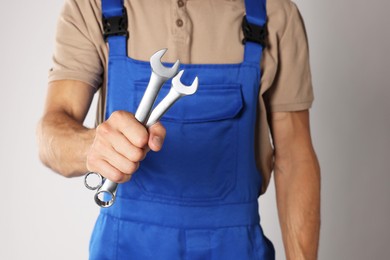 Auto mechanic with wrenches on light grey background, closeup