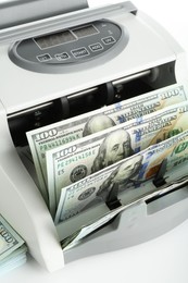 Photo of Money counter machine and dollar banknotes on white background, above view