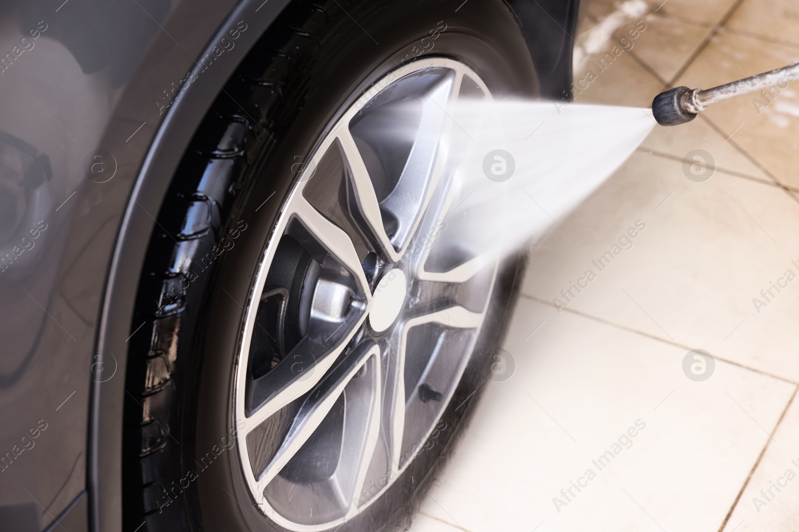 Photo of Washing auto with high pressure water jet at car wash, closeup