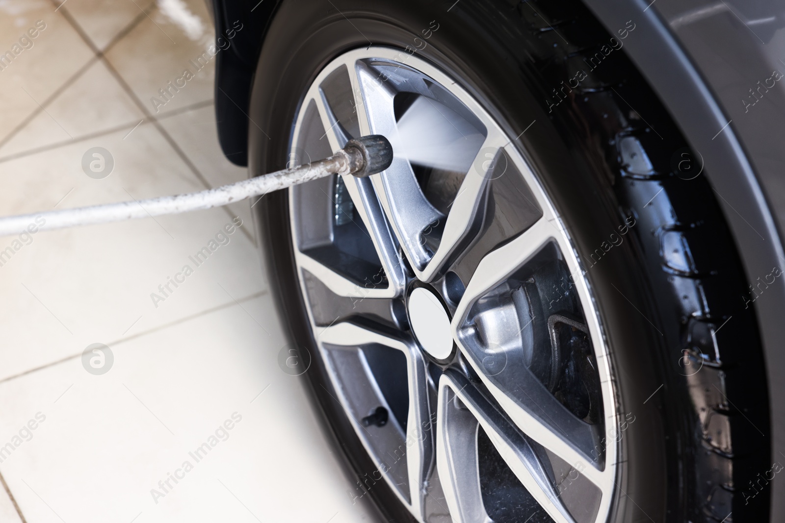 Photo of Washing auto with high pressure water jet at car wash, closeup