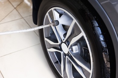 Washing auto with high pressure water jet at car wash, closeup