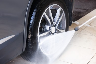 Washing auto with high pressure water jet at car wash, closeup