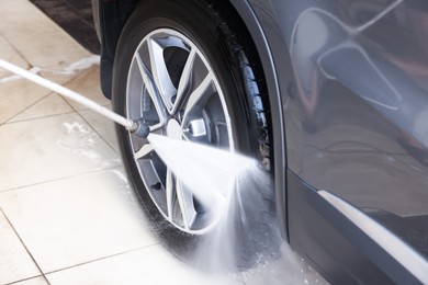 Washing auto with high pressure water jet at car wash, closeup