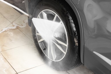 Washing auto with high pressure water jet at car wash, closeup