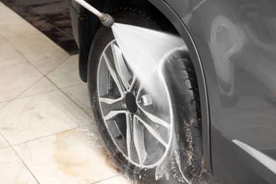 Photo of Washing auto with high pressure water jet at car wash, closeup