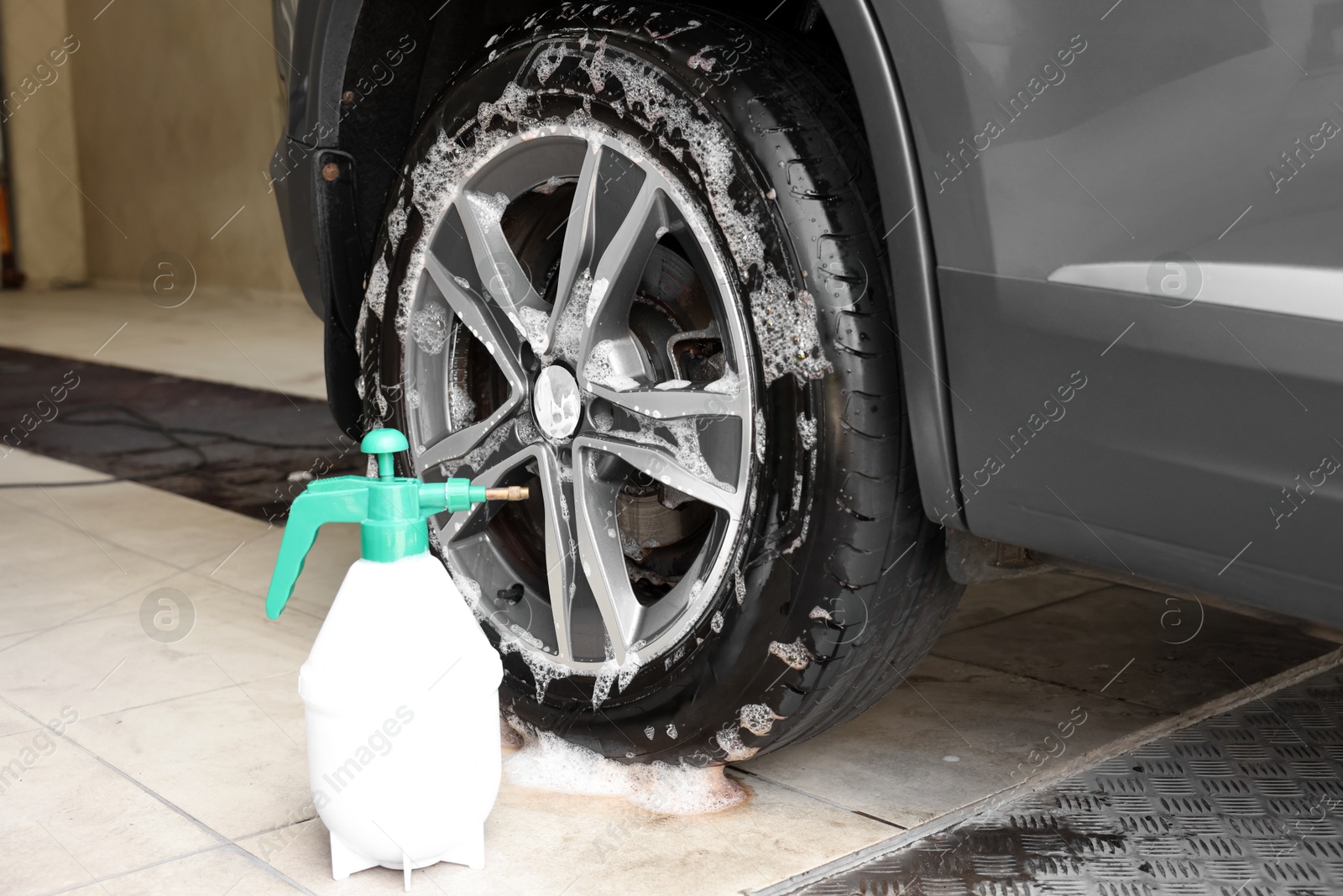 Photo of Sprayer near auto covered with cleaning foam at car wash