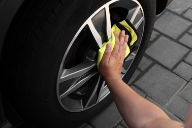 Man wiping car wheel with yellow rag, closeup