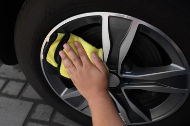 Man wiping car wheel with yellow rag, closeup