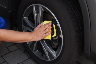 Photo of Man wiping car wheel with yellow rag, closeup