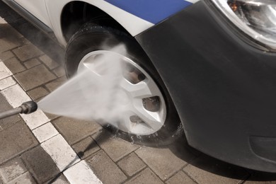 Washing auto with high pressure water jet at car wash, closeup