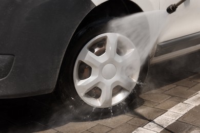 Washing auto with high pressure water jet at car wash, closeup