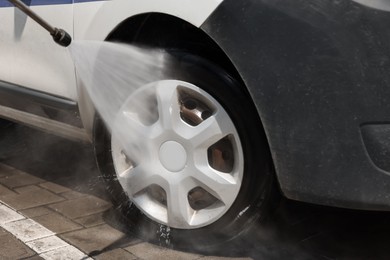 Washing auto with high pressure water jet at car wash, closeup