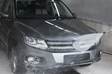 Photo of Washing auto with high pressure water jet at car wash, closeup