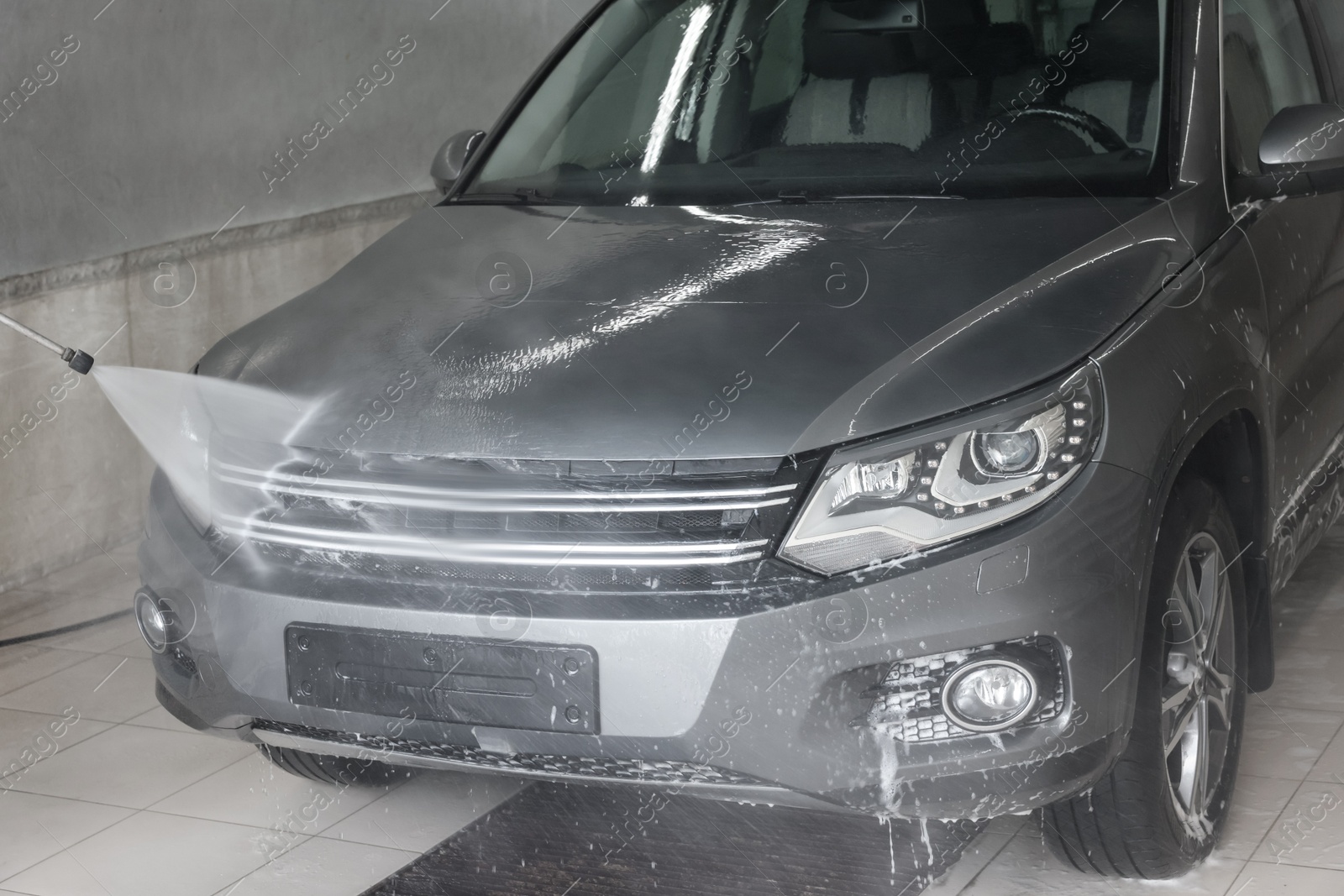 Photo of Washing auto with high pressure water jet at car wash, closeup