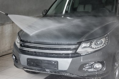 Washing auto with high pressure water jet at car wash, closeup