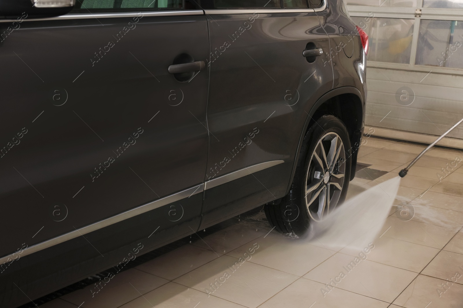 Photo of Washing auto with high pressure water jet at car wash, closeup