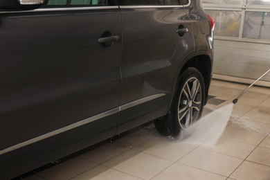 Washing auto with high pressure water jet at car wash, closeup