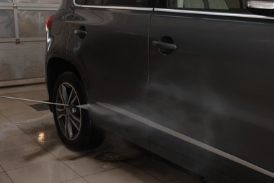 Washing auto with high pressure water jet at car wash, closeup