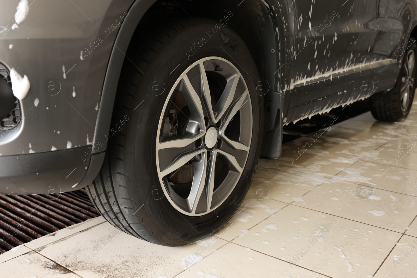 Photo of Auto covered with cleaning foam at car wash, closeup