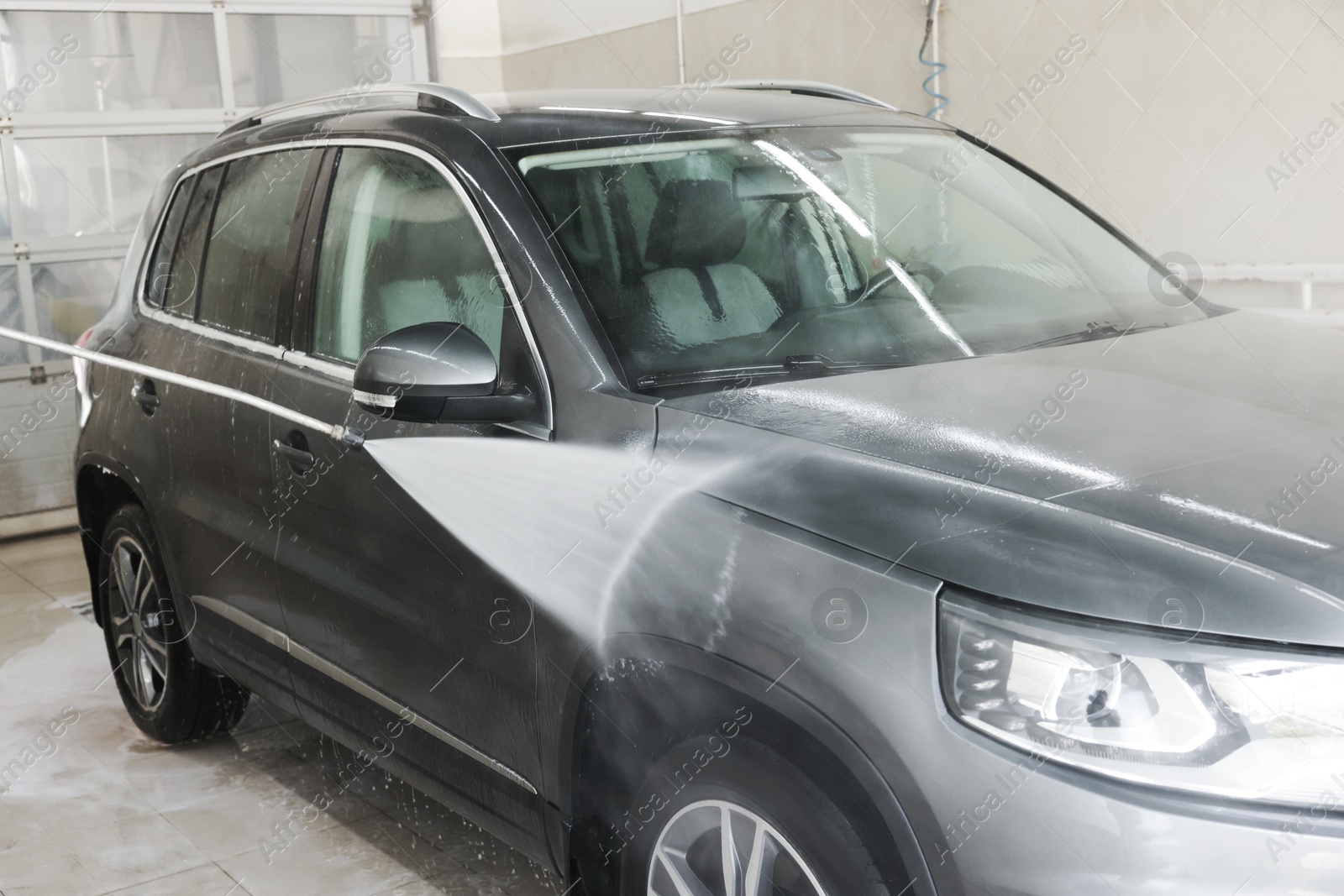 Photo of Washing auto with high pressure water jet at car wash, closeup