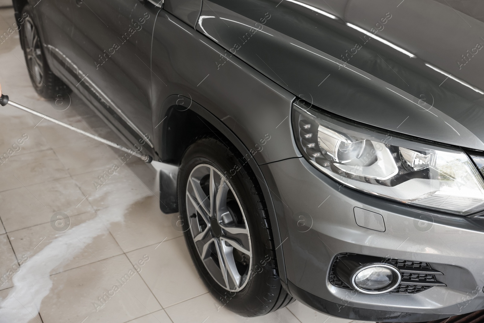 Photo of Washing auto with high pressure water jet at car wash, closeup