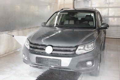 Washing auto with high pressure water jet at car wash, closeup