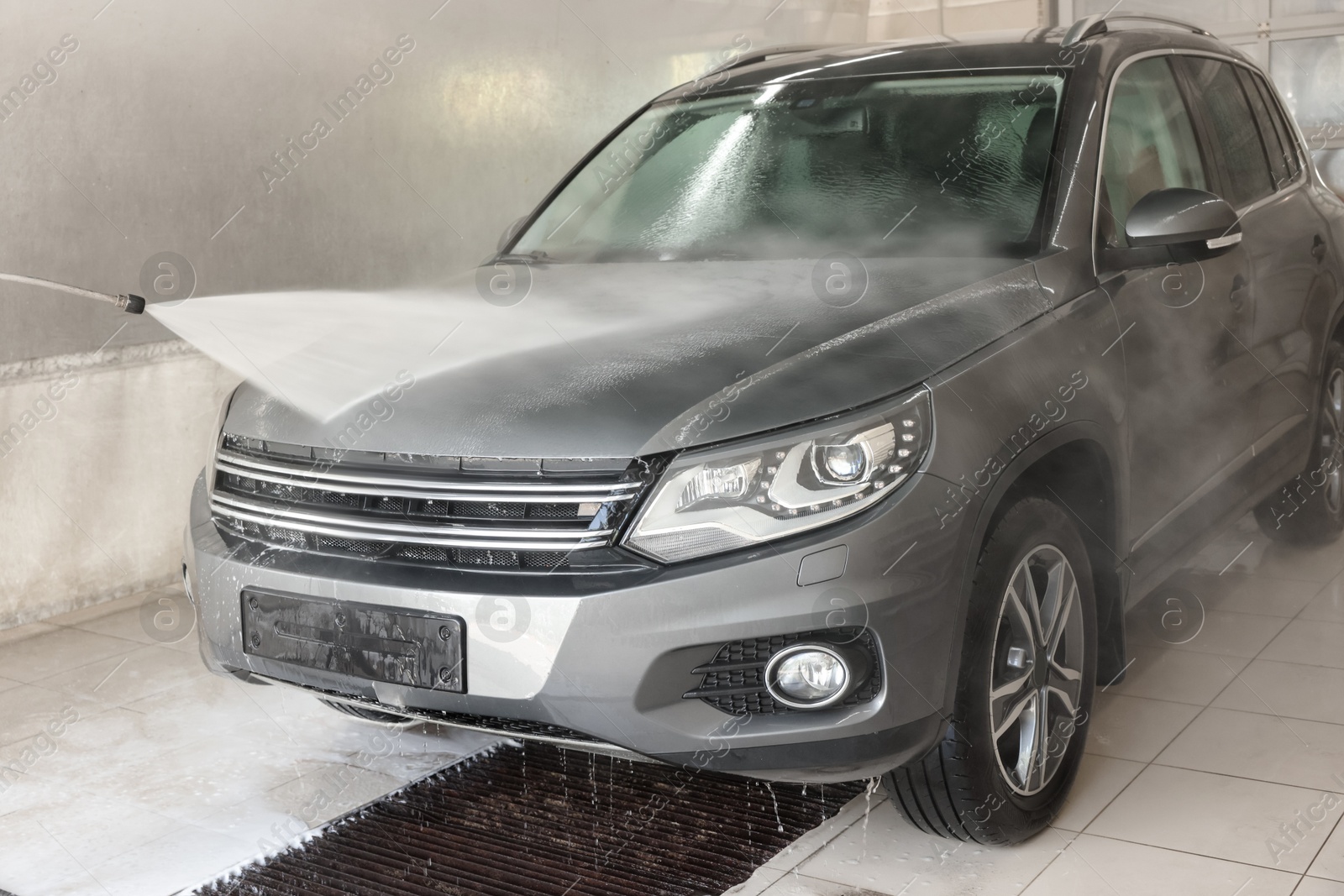 Photo of Washing auto with high pressure water jet at car wash, closeup