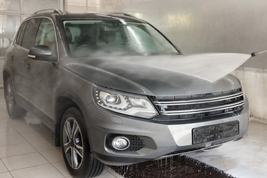 Photo of Washing auto with high pressure water jet at car wash, closeup