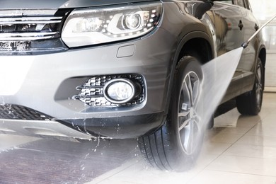 Washing auto with high pressure water jet at car wash, closeup