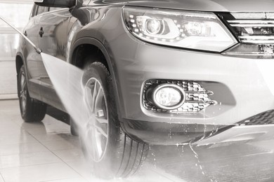 Photo of Washing auto with high pressure water jet at car wash, closeup