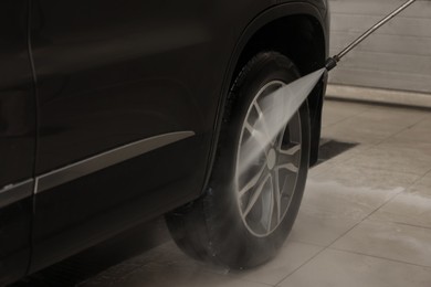 Photo of Washing auto with high pressure water jet at car wash, closeup