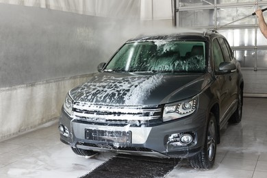 Man washing auto with high pressure water jet at car wash, closeup