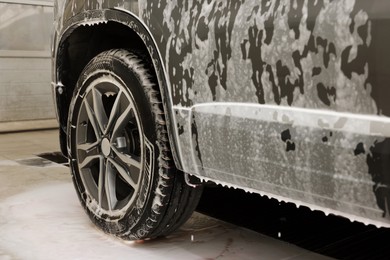 Photo of Auto covered with cleaning foam at car wash, closeup