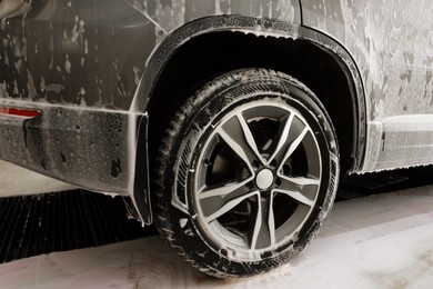 Auto covered with cleaning foam at car wash, closeup