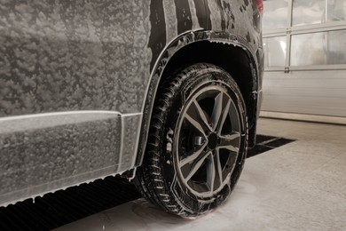 Photo of Auto covered with cleaning foam at car wash, closeup