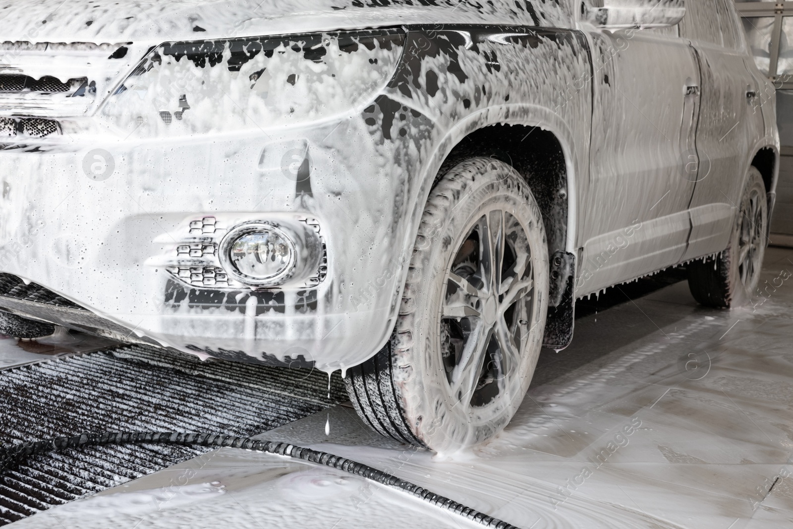 Photo of Auto covered with cleaning foam at car wash, closeup