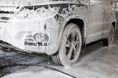 Auto covered with cleaning foam at car wash, closeup